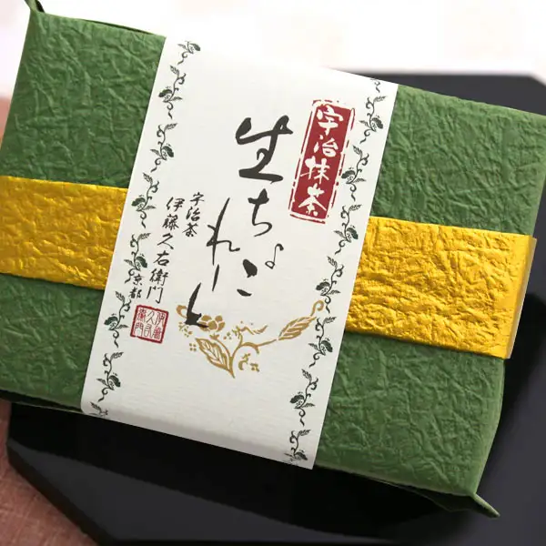 Photo of a box wrapped in green washi paper with a gold band and a white label. Text the store placed on the image: “宇治抹茶” (Uji matcha), “生ちょこれーと” (nama chocolate), “宇治茶 伊藤久右衛門 京都” (Uji tea, Itohkyuemon, Kyoto), and the Itohkyuemon seal. Itohkyuemon Uji Matcha Nama Chocolate, 16 Pieces, Matcha Flavor