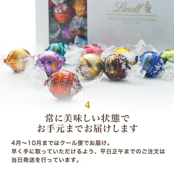 手前に赤・金・紫・青・緑などの個包装のリンドールが並び、奥にLindtのロゴ入りの白い箱が薄く写る写真。店舗が画像に入れた表示:「4」「常に美味しい状態でお手元までお届けします」「4月〜10月まではクール便でお届け。」「早く手に取っていただけるよう、平日正午までのご注文は当日発送を行っています。」