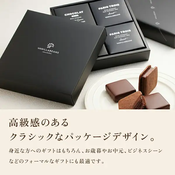 ショーコラ&パリトロ 4個入(バニラビーンズ)の商品写真。ふたを外した黒いギフト箱に黒い個箱が並び、見えている3つのうち1つに「CHOCOLAT」「Bitter chocolate」、2つに「PARIS TROIS」「Sweet」「VANILLABEANS」の文字。手前に「VANILLABEANS chocolatier」のロゴ入りの黒いふた、右手前の白い皿にチョコレートでコーティングされた四角いパリトロ2個と、クッキーでチョコレートをはさんだショーコラ(立てた1個と、切って断面を見せた1切れ)。店舗が画像に入れた表示「高級感のあるクラシックなパッケージデザイン。」「身近な方へのギフトはもちろん、お歳暮やお中元、ビジネスシーンなどのフォーマルなギフトにも最適です。」