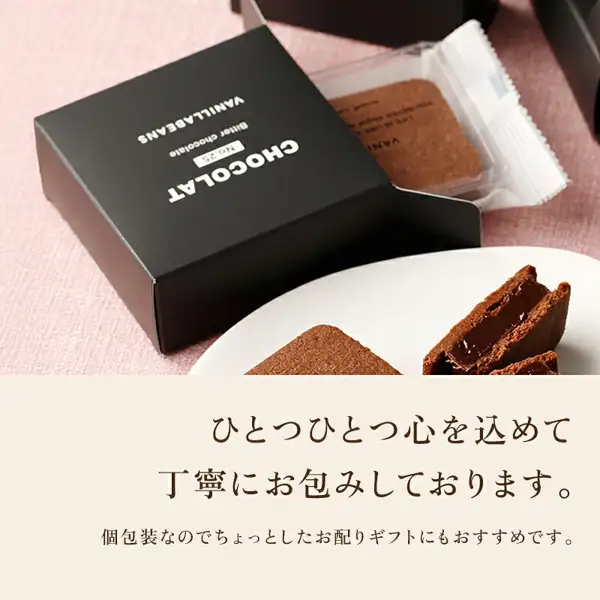 ショーコラ&パリトロ 4個入(バニラビーンズ)のショーコラの個箱と個包装の写真。ピンクの布の上に、白い文字で「CHOCOLAT」「No.25」「Bitter chocolate」「VANILLABEANS」と書かれた黒い個箱が置かれ、開いた口から透明の個包装に入ったショーコラが出ている。手前の白い皿にはショーコラ1個と、切って断面を見せたショーコラ。店舗が画像に入れた表示「ひとつひとつ心を込めて丁寧にお包みしております。」「個包装なのでちょっとしたお配りギフトにもおすすめです。」