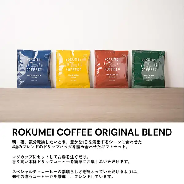 Product photo of four drip bags, one of each blend, standing on a wooden shelf; from the left the bags read SARUSAWA (blue), KASUGA (yellow), ROKUMEI (red) and MIKASA (green) (ROKUMEI COFFEE Drip Bag Coffee, 4 Blends, 10 Bags (Gift)). Text the store put in the image (translated from Japanese except the first line): “ROKUMEI COFFEE ORIGINAL BLEND”, “For mornings, nights, or whenever you want a change of pace: a gift set of drip bags in 4 blends matched to scenes that make for a richer day.”, “Just set it on a mug and pour in hot water. Enjoy aromatic, authentic drip coffee with ease.”, “To let you taste the wonder of specialty coffee, we carefully select coffee beans with distinct characters and blend them.”