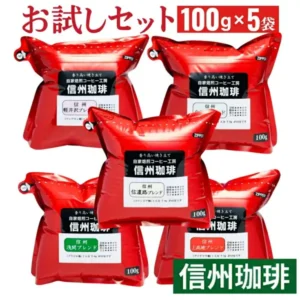 信州珈琲 お試しセット5種 500gの商品写真。「信州珈琲」のラベルを貼った赤いジッパー付きの袋5つが、上段2つ・中段1つ・下段2つの配置で並んでいる。画像内に店舗が画像に入れた表示として「お試しセット」「100g×5袋」「信州珈琲」「香り高い焼き立て」「自家焙煎コーヒー工房」「軽井沢ブレンド」「信濃路ブレンド」「浅間ブレンド」「上高地ブレンド」「(マンデリン他)」「(コロンビア他)」「(ブラジル他)」「(グアテマラ他)」「1人分 7-8g が目安です」「100g」の文字と、ラベルの甘味・酸味・苦み・コクの星印あり