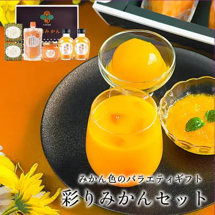 早和果樹園 彩りみかんセット（蜜柑组合套装）的商品照片。左上方是印有“早和”标志的黑色盒子，以及蜜柑果冻2盒、おふくろスムージー袋装1个、なめらかみかんジャム瓶装1个、飲むみかん瓶装2瓶；前方黑色盘子上摆放着一杯含果肉的蜜柑色饮品、一个装有整颗蜜柑果冻的器皿，以及一个放有薄荷叶的蜜柑色内容物器皿（摆盘示例。器皿、薄荷叶和花不包含在商品内）。店铺在图片中加入的标示“みかん色のバラエティギフト”“彩りみかんセット”