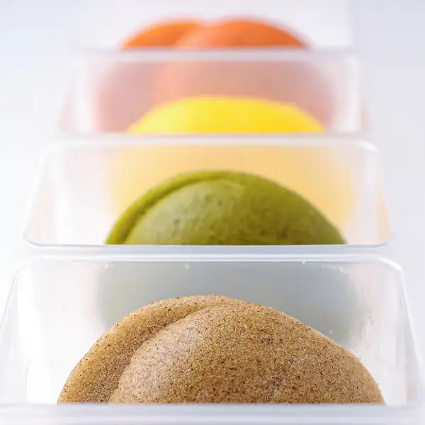 Close-up product photo of the Miyazaki Caviar 1983 (12g) & Blini Set: four blini, each in its own tray, lined up from brown in front to green, yellow and orange behind. No text in the image.