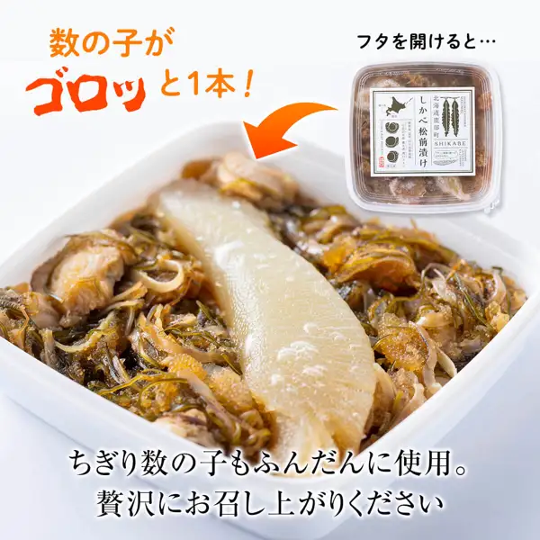 Plating-example photo of Shikabe Matsumae-zuke moved into a white square dish, with one whole kazunoko (herring roe) in the center surrounded by scallops, shredded kelp, dried squid and broken kazunoko, plus a lidded container labeled “北海道鹿部町” “しかべ松前漬け” “SHIKABE” at the upper right (Shikabe Matsumae-zuke with kazunoko, scallop and kelp). The dish is not included. Text the seller placed in the image: “数の子がゴロッと1本!” “フタを開けると…” “ちぎり数の子もふんだんに使用。贅沢にお召し上がりください”