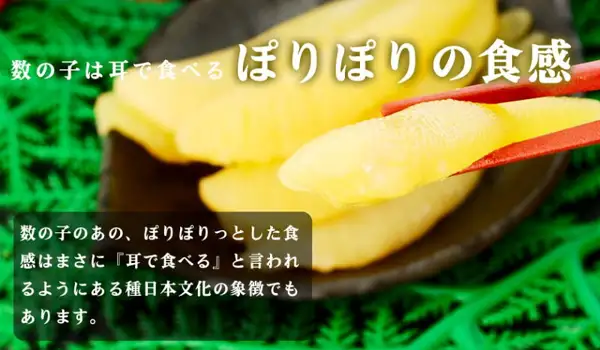 Close-up photo of a piece of seasoned kazunoko lifted with chopsticks, with more kazunoko on a plate in the back and green leaves in the background. Text the shop placed in the image: 「数の子は耳で食べる ぽりぽりの食感」 (kazunoko is eaten with the ears: a crunchy texture) and 「数の子のあの、ぽりぽりっとした食感はまさに『耳で食べる』と言われるようにある種日本文化の象徴でもあります。」 (that crunchy texture of kazunoko, said to be eaten with the ears, is in a sense a symbol of Japanese culture)