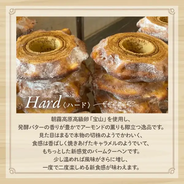 故乡纳税回礼品「ばあむくん かため」的商品页面图片。外形像树桩、中间有孔的年轮蛋糕（バウムクーヘン）层层叠起，形成两堆，左右并排。左下角有手写体的「Hard」和「〈ハード〉」（硬质）字样。店铺自行加入图片的文字：「Hard〈ハード〉」（硬质）「朝霧高原高級卵『宝山』を使用し、発酵バターの香りが豊かでアーモンドの薫りも際立つ逸品です。見た目はまるで本物の切株のようでかわいく、食感は香ばしく焼きあげたキャラメルのようでいて、もちっとした新感覚のバームクーヘンです。少し温めれば風味がさらに増し、一度で二度楽しめる新食感が味わえます。」（销售文案：使用朝雾高原的高级鸡蛋“宝山”，发酵黄油的香气浓郁，杏仁的香味也很突出；外形酷似真正的树桩，十分可爱；口感像烤得香脆的焦糖，却又软糯有嚼劲，是全新感觉的年轮蛋糕；稍微加热会让风味更浓，一次就能享受两种口感）。