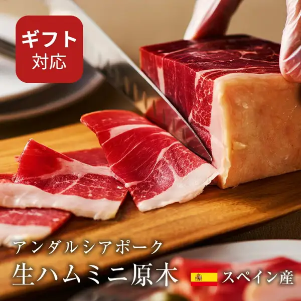 生ハム専用豚肉 アンダルシアポーク ミニ原木的商品照片。木砧板上，刀正切向一块生火腿，前方摆着切成薄片的生火腿。店铺放入图片的标示「ギフト対応」「アンダルシアポーク 生ハムミニ原木」「スペイン産」。
