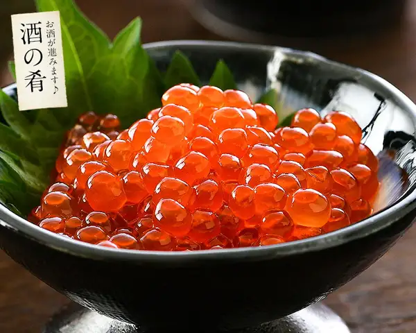 Product photo of trout roe marinated in soy sauce heaped in a black footed bowl, with green shiso leaves laid beneath it. Text the shop placed in the image: 「酒の肴」 (a snack for drinks) and 「お酒が進みます♪」 (goes well with sake).
