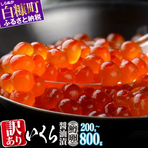 いくら醤油漬け 訳あり 鱒卵 200g〜800g（北海道白糠町故乡纳税）的商品照片。用勺子舀起盛在黑色器皿中、颗粒有光泽的鱼子。图片中有店铺自行加入的文字「しらぬか 白糠町 ふるさと納税」（白糠町故乡纳税）「訳あり」（规格外）「いくら」（鱼子）「醤油漬」（酱油渍）「鱒卵」（鳟鱼卵）「200g~800g」。