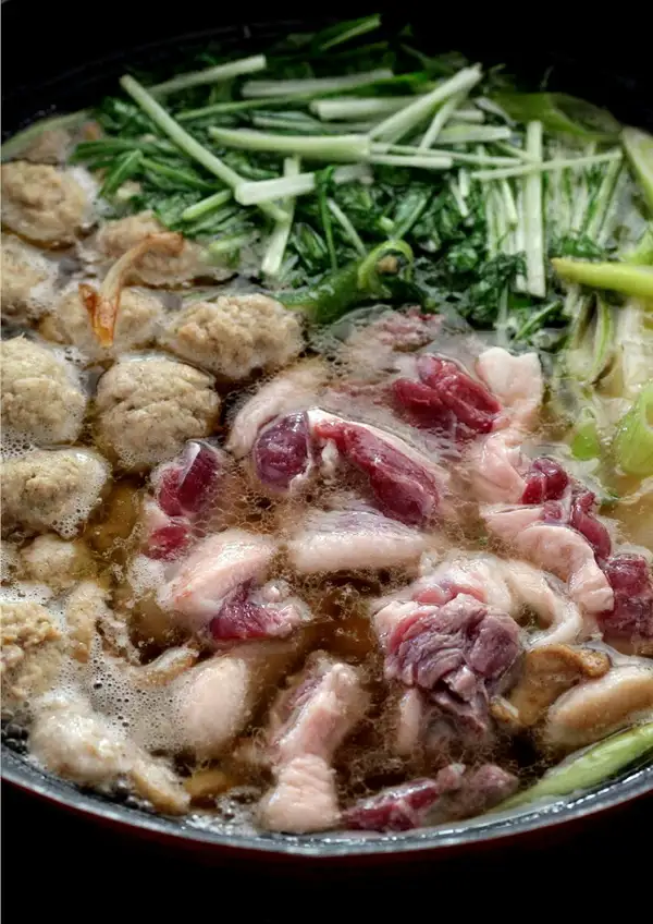 从上方拍摄的锅中加入鸭腿肉、鸭肉丸、水菜和葱煮好的鸭肉火锅照片。此为盛装示例,水菜、葱等蔬菜不包含在商品中(豊代 鴨三昧 岩手がも鍋セット)