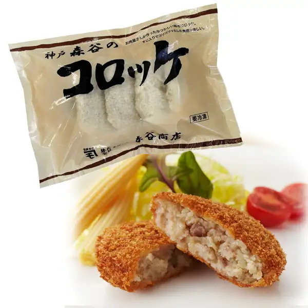 神戸森谷のコロッケ 10個（本神戸肉森谷商店）の商品写真。「神戸 森谷の」「コロッケ」「森谷商店」「要冷凍」「お肉屋さんが作ったなつかしい味のコロッケ。」「すじ入りでコリコリッとした食感が楽しい。」と印字された袋に入った揚げる前の白い衣のコロッケと、手前に割って断面を見せた揚げたコロッケ2個、ヤングコーン・葉物野菜・ミニトマト。