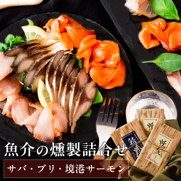 将鲭鱼・鰤鱼・境港三文鱼的烟熏鱼薄片与柠檬、绿叶菜一起摆在黑色盘中，旁边放有叉子、玻璃杯及3袋木纹包装商品的商品照片（風味絶佳.山陰 魔法のスモーク 烟熏海鲜组合）。店铺在图片中加入的标示：「魚介の燻製詰合せ」「サバ・ブリ・境港サーモン」