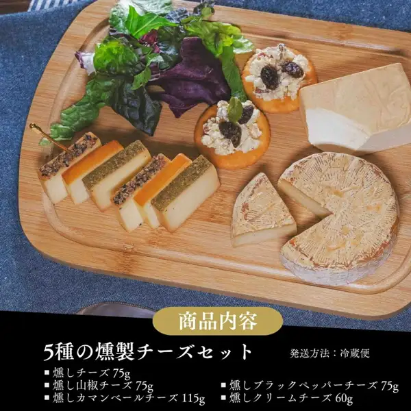 木のまな板に、スライスした燻製チーズ、ブラックペッパーをのせたチーズ、カマンベールタイプのチーズ、クリームチーズのブロックが並び、レーズンをのせたクラッカーとサラダ菜が添えられた写真。クラッカーとその上の具、サラダ菜は商品に含まれない盛り付け例。下部に店舗が画像に入れた表示：「商品内容」「5種の燻製チーズセット」「発送方法：冷蔵便」「燻しチーズ 75g」「燻し山椒チーズ 75g」「燻しブラックペッパーチーズ 75g」「燻しカマンベールチーズ 115g」「燻しクリームチーズ 60g」