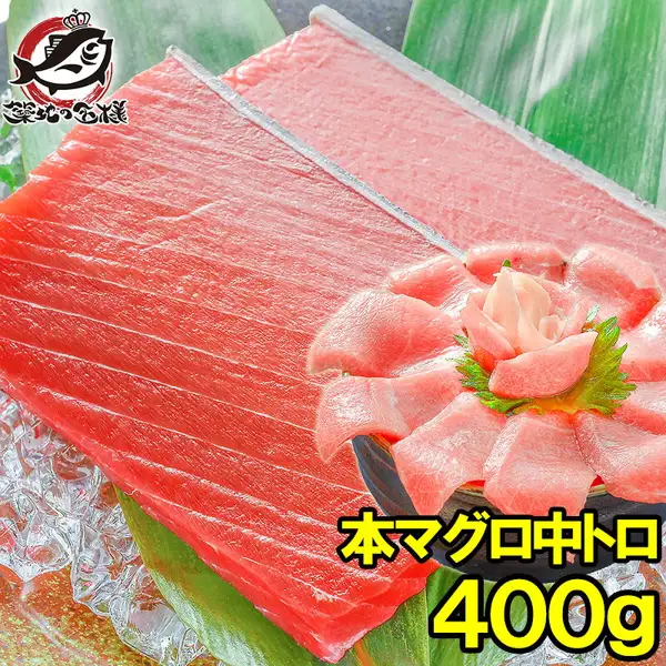 築地の王様 極上 本まぐろ 中トロ 400g的商品照片。冰块和竹叶上放着2块红色的中トロ（金枪鱼中腹肉）切块，右下方的碗里把中トロ切片摆成花朵状，配有紫苏叶和姜。碗里的摆盘为装盘示例，姜、紫苏叶和碗不包含在商品内。店铺在图片中加入的标示「本マグロ中トロ」「400g」（左上角为店铺标志「築地の王様」）