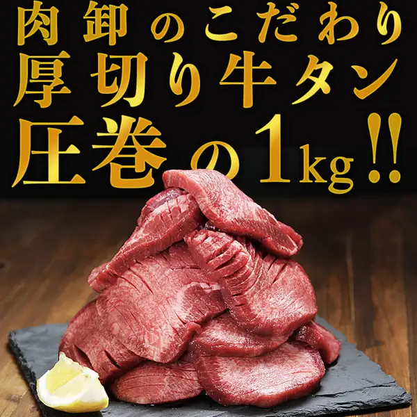 牛タン 訳あり 厚切り 1kgの商品画像。黒いスレートの皿に切れ目の入った厚切りの牛タンが山のように盛られ、左下にレモンが添えられている。上部に店舗が画像に入れた表示「肉卸のこだわり」「厚切り牛タン」「圧巻の1kg!!」の文字が入っている