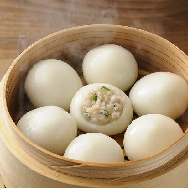 蒸笼中摆放着冒着热气的白色圆形じゃが豚的照片。中央的一个外皮裂开,可以看到猪肉和蔬菜馅料(佃善 じゃが豚 业务用1kg)