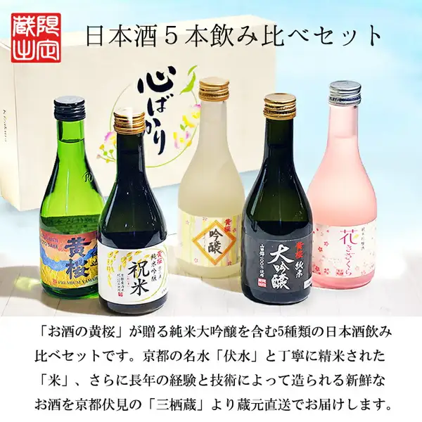 黄桜 日本酒 飲み比べ まごころセット 300ml×5本の商品写真。「心ばかり」と書かれたクリーム色の箱を背景に、左から緑のボトルの「黄桜」、「祝米」、クリーム色のボトルの「吟醸」、黒いボトルの「純米大吟醸」、ピンクのボトルの「花きざくら」の5本が並んでいる。左上に赤い角印あり。店舗が画像に入れた表示として「日本酒５本飲み比べセット」と、「「お酒の黄桜」が贈る純米大吟醸を含む5種類の日本酒飲み比べセットです。京都の名水「伏水」と丁寧に精米された「米」、さらに長年の経験と技術によって造られる新鮮なお酒を京都伏見の「三栖蔵」より蔵元直送でお届けします。」の文字あり