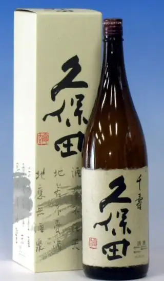 久保田 千寿 吟醸 1800ml的商品照片。蓝色背景左侧是印有「久保田」字样和红色方印的淡黄绿奶油色盒子，右侧立着一只茶色一升瓶。酒瓶的和纸风格标签上可见「千寿」「久保田」「清酒」字样和红色方印