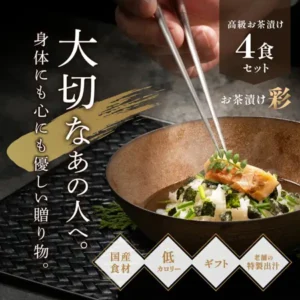 恵み茶屋高级お茶漬け（茶泡饭）礼盒“彩”4食套装的商品照片。棕色的碗里盛着米饭，上面放着带烤色的鱼块、海苔和切碎的绿色佐料，一只手正用筷子放上装饰叶。图片中店铺自行加入的标示有：“高級お茶漬け 4食 セット”“お茶漬け 彩”“国産食材”“ギフト”“老舗の特製出汁”。