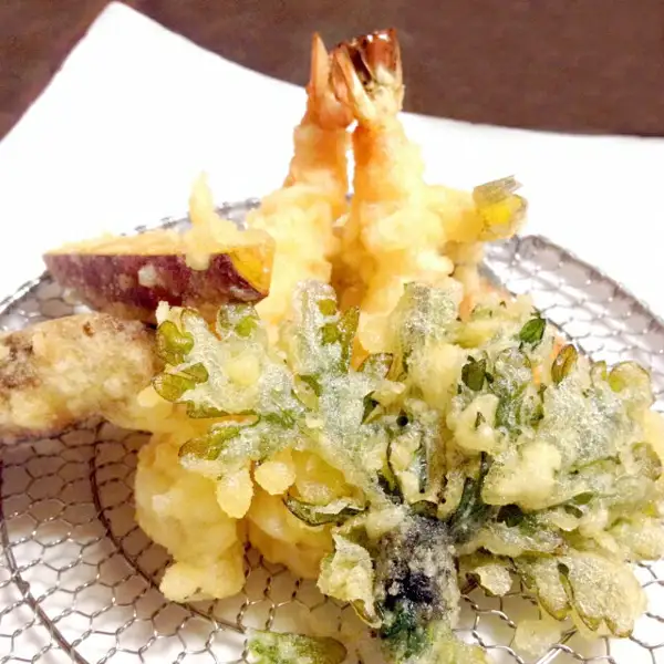 Photo of a cooking example: tempura of shrimp, sweet potato and leafy greens served on a white plate set on a wire mesh rack