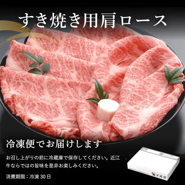 黑色圆盘中铺开的霜降牛肩里脊肉片配有装饰叶片和白色装饰物，右下方可见印有店名“千成亭”的白色礼盒的商品照片（千成亭 近江牛 肩ロース（肩里脊）すき焼き（寿喜烧）用500g）。店铺放入图片的标示文字：“すき焼き用肩ロース”（寿喜烧用肩里脊）、“冷凍便でお届けします”（以冷冻配送送达）、“お召し上がりの前に冷蔵庫で保存してください。近江牛ならではの旨味を是非お楽しみください。”（食用前请冷藏保存，请享受近江牛特有的鲜味）、“消費期限：冷凍 30日”（消费期限：冷冻30天）