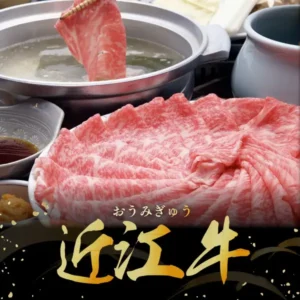 湯を張った鍋に箸で薄切りの牛肉をくぐらせる様子と、皿に広げた霜降りの牛肉スライス、左に茶色のたれと薬味の小鉢、鍋の奥に豆腐やねぎとみられる具材が写る商品写真（千成亭 近江牛 肩ロース しゃぶしゃぶ 500g）。店舗が画像に入れた表示として「おうみぎゅう」「近江牛」の文字