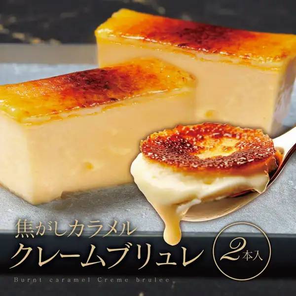 クレームブリュレ(焦糖布蕾)2本入 カタラーナ(卡塔兰娜)的商品照片。灰色石板上并排放着2条表面焦糖化的长条形布蕾,前方的勺子上舀着正流下浓稠蛋奶酱的一块。店铺自行加入图片的标示有「焦がしカラメル クレームブリュレ 2本入」(焦糖布蕾2本入)、「Burnt caramel Creme brulee」