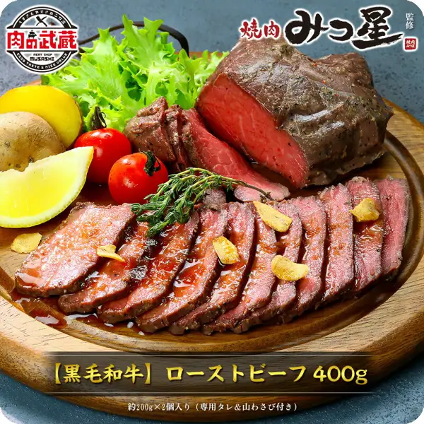 Photo of sliced roast beef and a block of roast beef served on a wooden plate with lemon, cherry tomatoes, potatoes, frisée lettuce, thyme, and garlic chips, as a plating example (甲羅組 Roast Beef 400g (2 pieces of 200g)). Text the shop placed in the image reads “肉の武蔵” (Niku no Musashi), “焼肉みつ星 監修” (supervised by the yakiniku restaurant Mitsuboshi), “【黒毛和牛】ローストビーフ 400g” (Kuroge Wagyu roast beef, 400g), and “約200g×2個入り（専用タレ＆山わさび付き）” (approx. 200g × 2 pieces, with dedicated sauce and yamawasabi, a Japanese horseradish)