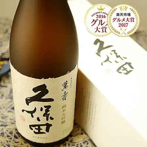 近距离拍摄久保田 萬寿 純米大吟醸 1800ml标签的商品照片。标签上写有「萬壽」「久保田」「純米大吟醸」「KUBOTA」，后方可见白色盒子。作为店铺自行加入图片的标示，右上角有「GOURMET AWARD 2016 グルメ大賞」「楽天市場 グルメ大賞 2017」2个徽章