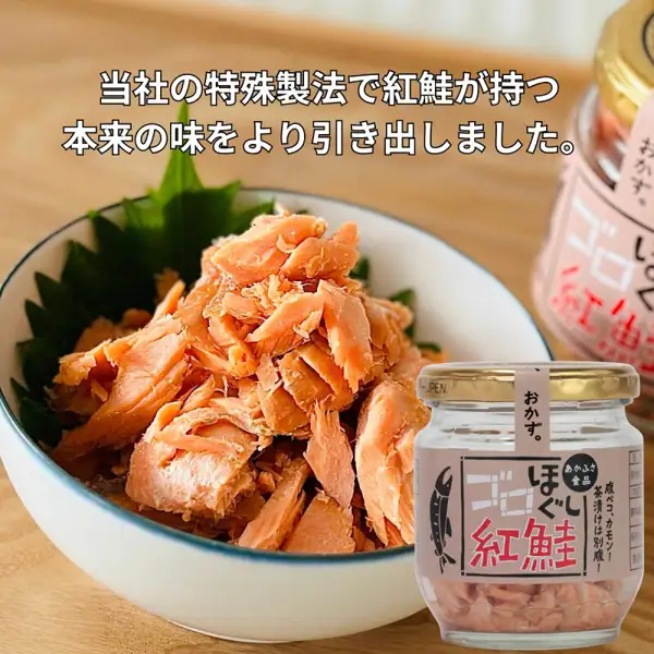 ゴロほぐし鮭フレーク(鲑鱼松)80g 6瓶套装(あかふさ食品)的商品图片(第6瓶的选项之一,红鲑瓶的示例,紫苏叶和碗不包含在商品内)。白色碗中垫着紫苏叶,盛有红橙色的红鲑肉松,右侧是一瓶标签为「ゴロほぐし 紅鮭」的瓶子。店铺在图片中标示的文字:「当社の特殊製法で紅鮭が持つ本来の味をより引き出しました。」,瓶身标签上有「あかふさ食品」「おかず。」「腹ペコ、カモン!茶漬けは別腹!」
