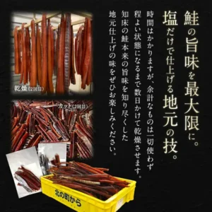 吊り下げて乾燥させている細長い鮭の身、カットした鮭とばを並べた様子、黄色いコンテナに入れた鮭とばと袋入りの鮭とばを写した説明画像の写真（北の町から 漁師が作る鮭とば 80g）。画像内に店舗が画像に入れた表示として「鮭の旨味を最大限に。塩だけで仕上げる地元の技。」「時間はかかりますが、余計なものは一切使わず程よい状態になるまで数日かけて乾燥させます。知床の鮭本来の旨味を知り尽くした地元仕上げの味をぜひお楽しみください。」「乾燥（2回目）」「カット（2回目）」の文字、黄色いコンテナに「北の町から」の文字あり