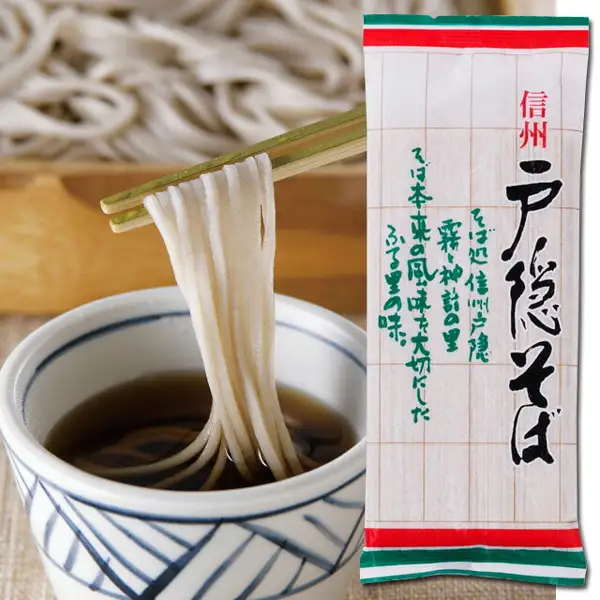 商品照片：左侧是用筷子夹起荞麦面、蘸入带蓝色花纹的白碗中的褐色蘸汁（つゆ）的情形，右侧是细长的信州戸隠そば袋装（白底绿色格线，上下有红色和绿色横条），背景可见木台上的荞麦面。袋上印有「信州」「戸隠そば」「そば処信州戸隠 霧と神話の里 そば本来の風味を大切にしたふる里の味。」（袋上的印字）。蘸汁（つゆ）是盛放示例，商品页面的套装内容中没有记载。信州戸隠そば お試しセット