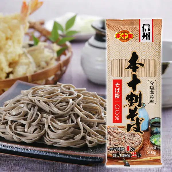 商品照片：左侧是盛有虾等天妇罗的竹篮与绿叶、黑色方盘上的荞麦面、装有蘸汁（つゆ）的酒壶和小碗，右侧是本十割そば的袋装（200g）。袋上印有「信州」、红色圆形的「本十割」标志、「本十割そば」「そば粉100%」「食塩無添加」「ゆで時間4分」「むらし時間2分」「内容量200g」（袋上的印字）。天妇罗、蘸汁（つゆ）和餐具是盛放示例，商品页面的套装内容中没有记载。信州戸隠そば お試しセット