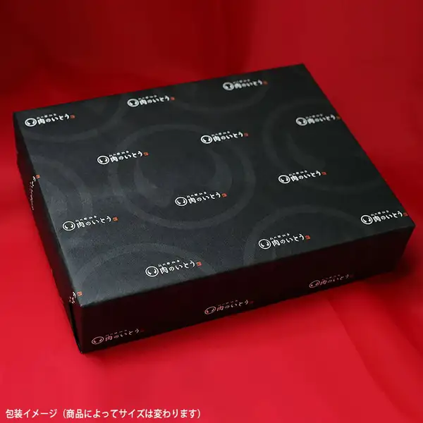 The seller's wrapping image photo for Sendai Gyu sirloin steak, 200–220g × 2 pieces: a flat box wrapped in black paper patterned with the shop logo “肉のいとう” in white, placed on a red cloth. At the bottom left is the text “包装イメージ（商品によってサイズは変わります）” (wrapping image; size varies by product), placed in the image by the shop.