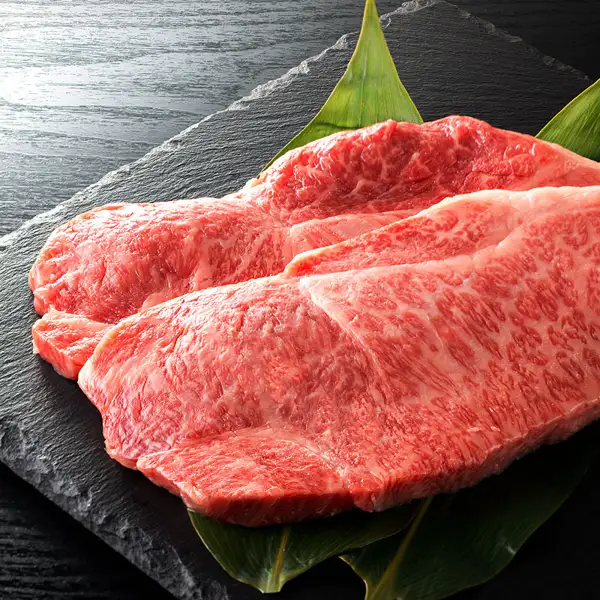 黒い石板の上に敷いた緑の笹の葉の上に、細かな霜降りの入った赤い牛サーロインステーキ肉を2枚重ねて並べた、仙台牛 サーロインステーキ 200〜220g×2枚の商品写真。