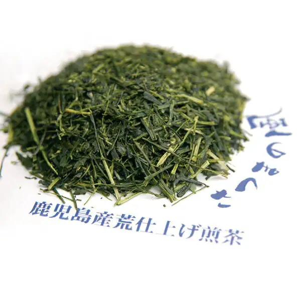 長峰製茶 さつまの風の茶葉の写真。白い紙の上に、細い葉と黄緑色の茎が混じった深緑色の茶葉が山盛りになっている。店舗が画像に入れた表示「鹿児島産荒仕上げ煎茶」、右側に一部だけ写った筆文字