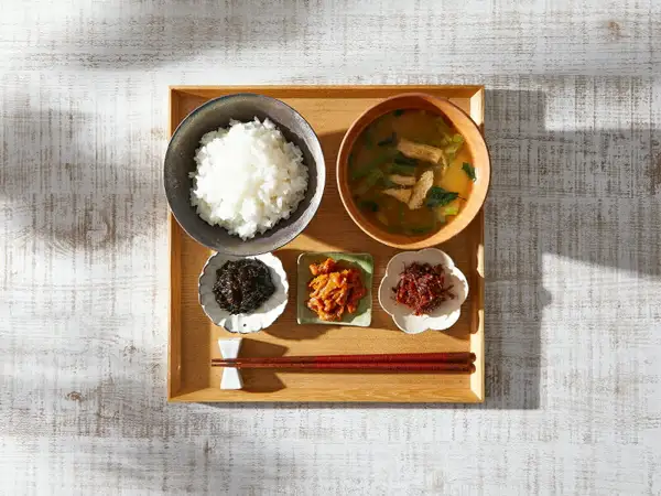 OKiNI 佃煮瓶3本セット 小倉屋山本の中身を盛り付けた例の写真。木のお盆に、ご飯、油揚げと青菜の味噌汁、小皿に盛ったのり佃煮・雲丹ほたて・おかか明太、箸が並ぶ。ご飯・味噌汁・お盆・器は盛り付けの例で、商品に含まれない。画像内に文字はない。