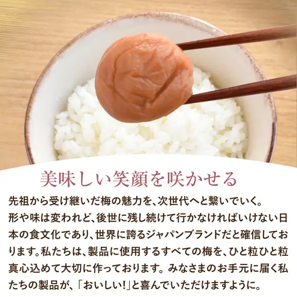 福梅本舗 特選紀州南高梅干し 食べ比べお試しセットの食べ方の例の写真。箸でつまんだ梅干し1粒を、茶色の縁のある器に盛った白いご飯の上に持ち上げた食べ方の例の写真。画像内に店舗が画像に入れた表示として「美味しい笑顔を咲かせる」、「先祖から受け継いだ梅の魅力を、次世代へと繋いでいく。」「世界に誇るジャパンブランドだと確信しております」「製品に使用するすべての梅を、ひと粒ひと粒真心込めて大切に作っております」「『おいしい！』と喜んでいただけますように」などの文章あり。ご飯は商品に含まれない