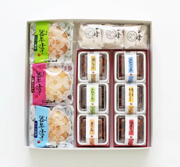 Product photo of the Tsukuda no Tsukudani (佃の佃煮) Oajimi Set: a white gift box holding 3 wrapped varieties of 器茶漬け (Utsuwa Chazuke, monaka), 3 wrapped pieces labeled “白峰” (Shiramine), and a tray of 6 labeled varieties of tsukudani