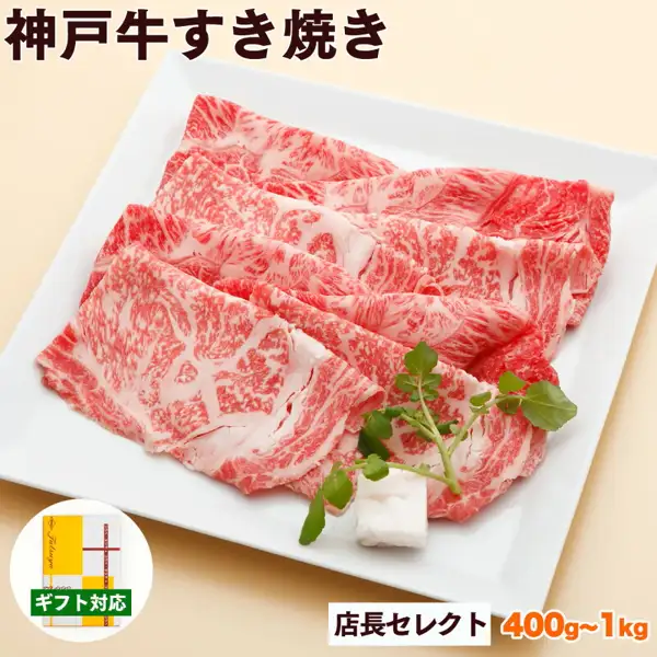 Product photo of Kobe Gyu Sukiyaki Meat, Tencho Select (神戸牛専門店 辰屋). Thinly sliced, marbled sukiyaki beef is arranged on a white square plate with a green leaf garnish. Text the shop placed in the image includes “神戸牛すき焼き”, “店長セレクト”, “400g~1kg”, and “ギフト対応” (gift-ready), plus a small round inset photo of a gift box in yellow and white wrapping paper at the lower left.