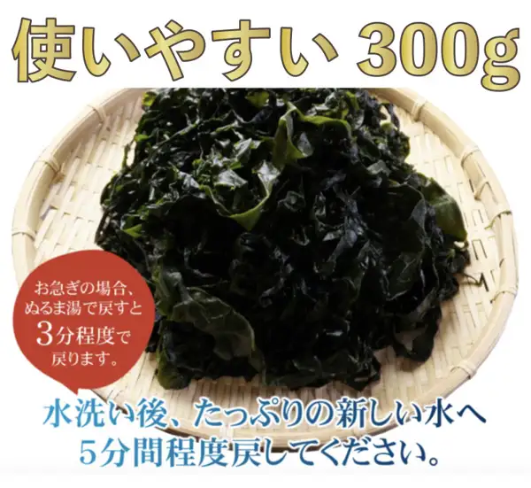 竹筛上堆满深绿色裙带菜的商品照片。上方写着「使いやすい 300g」,左下的红褐色圆圈里写着「お急ぎの場合、ぬるま湯で戻すと3分程度で戻ります。」,下方写着「水洗い後、たっぷりの新しい水へ5分間程度戻してください。」(店铺加入图片的标示)。黒潮海苔店 三陸産(岩手県野田村産)湯通し塩蔵わかめ(烫煮盐渍裙带菜)300g