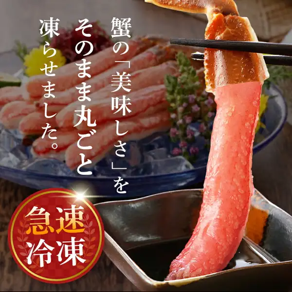 用筷子夹起一条雪蟹腿肉蘸入黑色酱碟的商品照片,背景是铺着冰块、点缀黄色和紫色花朵的蓝色玻璃盘中盛放的更多蟹腿肉(生本ずわいがに 棒肉ポーション)。图片中店铺自行加入的标示为「蟹の「美味しさ」をそのまま丸ごと凍らせました。」「急速冷凍」。冰块、花朵、酱碟和筷子为摆盘装饰。